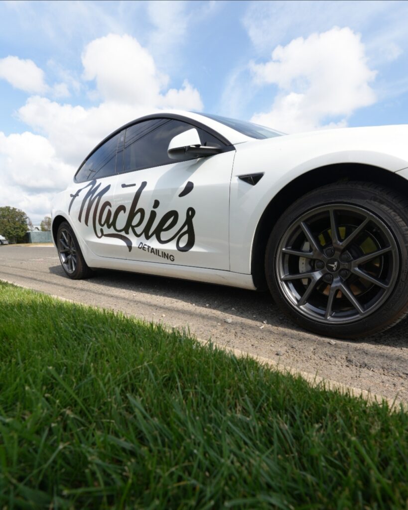Low-angle view of Mackie’s Detailing branded service vehicle parked roadside, highlighting the company logo and professional mobile auto detailing services.