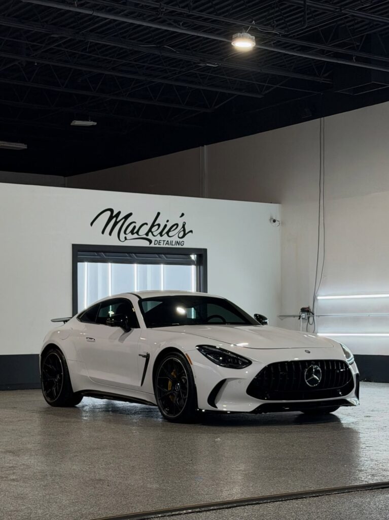 White Mercedes-AMG sports car inside Mackie’s Detailing studio, showcasing a freshly detailed exterior with deep gloss and precision finish under professional lighting.