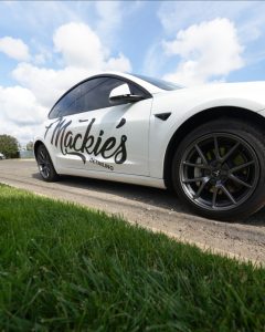 Low-angle view of Mackie’s Detailing branded service vehicle parked roadside, highlighting the company logo and professional mobile auto detailing services.