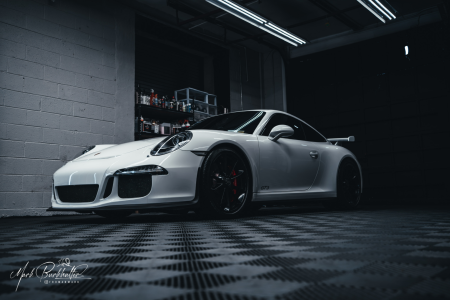 White Porsche 911 GT3 inside Mackie’s Detailing shop under dramatic lighting, highlighting precision detailing and showroom-quality finish.